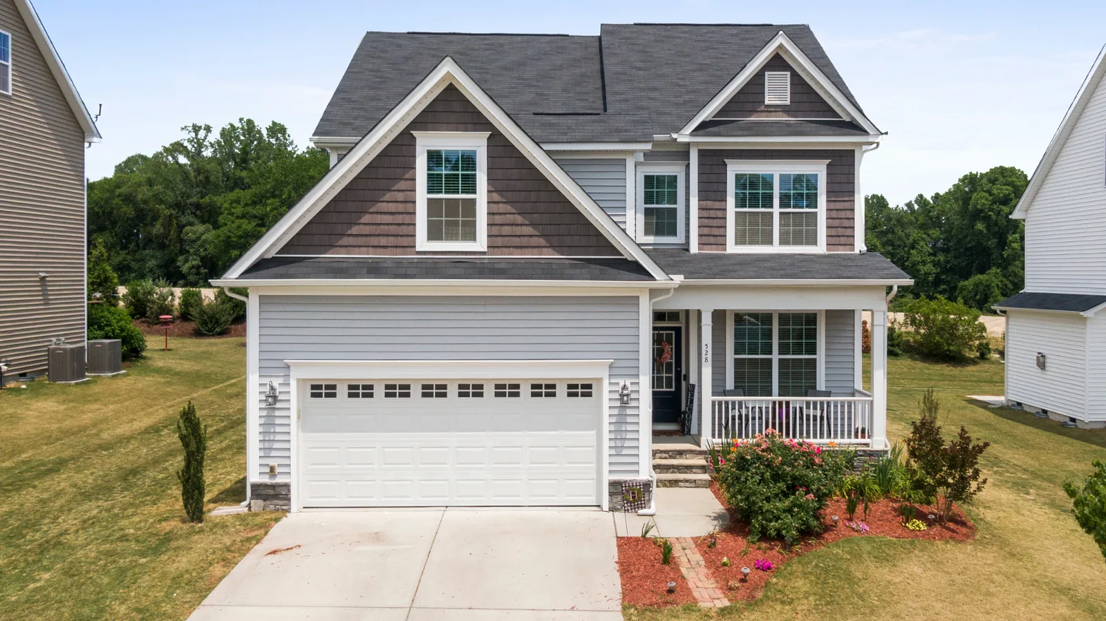 Two-story home with dark shingle roof and covered front porch